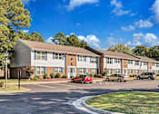 Thumbnail 5 of 30 - a parking lot with cars parked in front of an apartment building