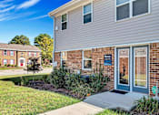 Thumbnail 2 of 30 - a sidewalk in front of a brick house with a blue door