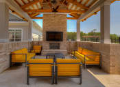 Thumbnail 26 of 34 - a covered patio with a fireplace and yellow couches