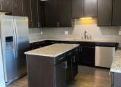 Thumbnail 5 of 29 - Modern kitchen with backsplash and island at Flats on 4th Apartments in Birmingham, AL
