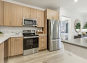 Thumbnail 4 of 39 - a modern kitchen with stainless steel appliances and wooden cabinets at Tapestry Headwaters in Kissimmee, FL
