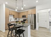 Thumbnail 1 of 39 - island kitchen with stainless steel appliances and designer lighting at Tapestry Headwaters Apartments in Kissimmee, FL