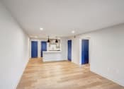 Thumbnail 11 of 28 - a living room and kitchen with white walls and wood flooring