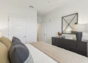 Thumbnail 16 of 39 - a bedroom with a large bed and a dresser with a mirror