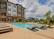 Thumbnail 13 of 38 - a swimming pool with lounge chairs in front of an apartment building