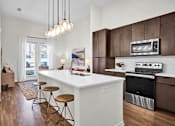 Thumbnail 1 of 55 - A modern kitchen with a white island, white countertop and brown cabinetry