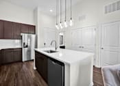 Thumbnail 7 of 55 - A modern kitchen with a white island and dark brown cabinets, high ceilings and beautiful lighting.