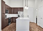 Thumbnail 11 of 55 - A modern and chef style kitchen with brown cabinets and a white island.