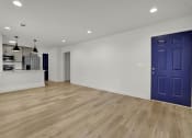 Thumbnail 14 of 28 - an empty living room with a blue door and a kitchen