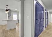 Thumbnail 18 of 28 - a hallway with blue doors leading to a kitchen and a counter top in a house