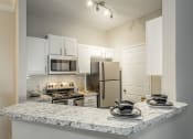 Thumbnail 6 of 25 - a kitchen with a granite counter top and a stainless steel refrigerator