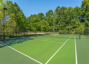 Thumbnail 22 of 25 - a tennis court with trees in the background on a clear day
