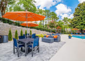 Thumbnail 27 of 35 - a patio with a table and chairs and an umbrella next to a swimming pool