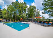 Thumbnail 26 of 35 - a swimming pool with chairs and umbrellas and trees