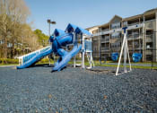 Thumbnail 31 of 35 - a playground with a blue slide and swings in front of an apartment building