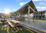 Thumbnail 12 of 24 - a deck with a picnic table and grill near swimming pool at Retreat at Brightside Apartments in Baton Rouge, LA