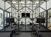 Thumbnail 10 of 22 - A room with a black and white geometric patterned wall and two stationary bikes.