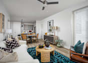 Thumbnail 15 of 22 - A living room with a white couch, a wooden coffee table, and a ceiling fan.