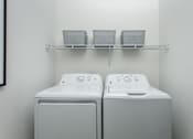 Thumbnail 22 of 22 - Two white washing machines are on a shelf in a laundry room.