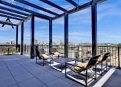 Thumbnail 31 of 55 - rooftop balcony with chairs and a table and a view of the city at Artisan Flats Apartments in Birmingham, AL