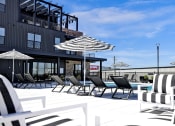 Thumbnail 30 of 55 - Pool Deck with Seating and Umbrellas at Artisan Flats Apartments in Birmingham, AL