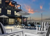 Thumbnail 2 of 55 - Pool Deck and Seating with Umbrellas at Artisan Flats Apartments in Birmingham, AL an outdoor patio with chairs and umbrellas at dusk at Artisan Flats in Birmingham, AL