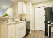 Thumbnail 26 of 34 - a kitchen with white cabinets and stainless steel appliances and a black refrigerator