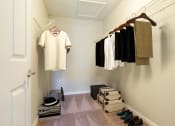 Thumbnail 29 of 34 - a walk in closet with clothes hanging on the wall and shoes on the floor