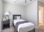 Thumbnail 13 of 25 - a bedroom with a bed and a nightstand and a mirror