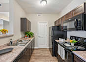 Thumbnail 1 of 21 - A kitchen with black appliances and brown cabinets.