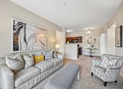 Thumbnail 4 of 21 - A living room with a grey couch and a large abstract painting on the wall.