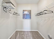 Thumbnail 9 of 21 - A walk-in closet with a window and a carpeted floor.
