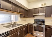 Thumbnail 8 of 19 - A kitchen with a stove, sink, and cabinets.