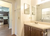 Thumbnail 12 of 19 - A bathroom with a sink, mirror, and wooden cabinets.