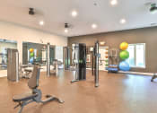 Thumbnail 16 of 25 - a gym with cardio equipment and weights in a building with windows