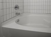 Thumbnail 54 of 55 - a white tiled bathroom with a tub and a shower at Artisan Flats in Birmingham, AL