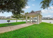 Thumbnail 29 of 33 - a gazebo with a picnic table on the grass next to the water