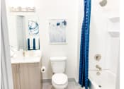 Thumbnail 12 of 34 - a bathroom with a white toilet and a blue shower curtain