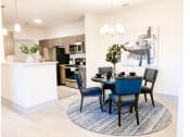Thumbnail 8 of 34 - a dining area with a table and chairs and a kitchen in the background