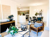 Thumbnail 5 of 34 - a living room with a couch and chairs and a kitchen in the background