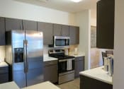 Thumbnail 4 of 21 - a kitchen with a stove a refrigerator and a microwave