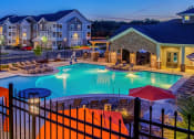 Thumbnail 2 of 21 - a resort style pool with lounge chairs and umbrellas at dusk
