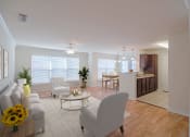 Thumbnail 5 of 34 - A living room with a grey sofa, a white chair and a coffee table with sunflowers on it at 10X Audubon Park apartments in Daphne, AL 