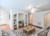 Thumbnail 6 of 34 - A living room with a couch, coffee table, and a ceiling fan at 10X Audubon Park apartments in Daphne, AL 