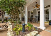 Thumbnail 27 of 34 - the front porch of a house with a courtyard and benches at 10X Audubon Park apartments in Daphne, AL 