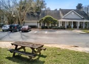 Thumbnail 33 of 34 - a picnic table in a parking lot in at 10X Audubon Park apartments in Daphne, AL  front of a house