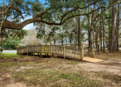 Thumbnail 23 of 34 - A wooden deck is surrounded by trees in a wooded area at 10X Audubon Park apartments in Daphne, AL 