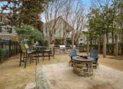 Thumbnail 18 of 34 - a patio with chairs and a fire pit at 10X Audubon Park apartments in Daphne, AL 