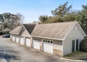 Thumbnail 26 of 34 - a car garage with white doors and a parking lot at 10X Audubon Park apartments in Daphne, AL 