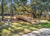 Thumbnail 24 of 34 - a wooden bridge in a park with trees and a gazebo at 10X Audubon Park apartments in Daphne, AL 